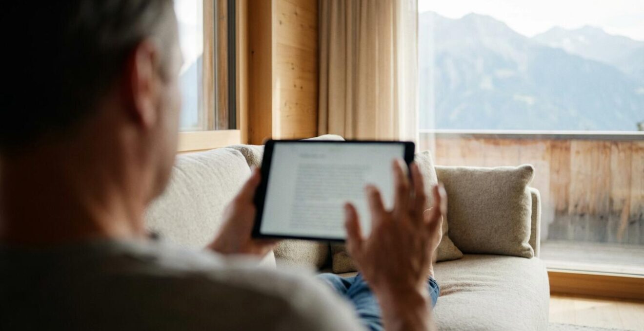 Person nutzt Tablet für Immobilienbewertung in hellem Schweizer Wohnzimmer